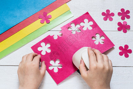 儿童用粉红色纸做特别的洞拳花纸板和白木桌切花图片