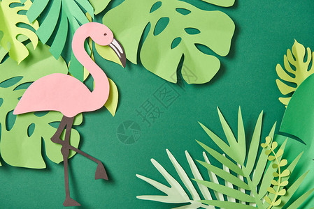 绿色背景中异国情调的剪纸棕榈叶和粉红色火烈鸟的顶视图图片