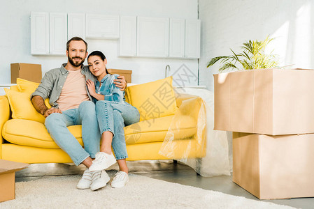 微笑的丈夫和妻子拥抱和坐在沙发上图片