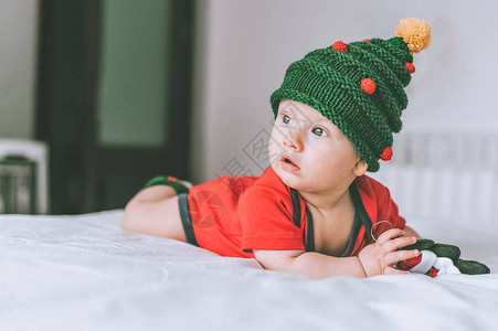 穿着圣诞节编织的帽子和床上穿红色整身红背景图片