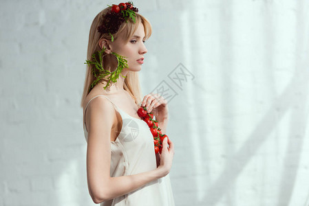 年轻女一面手拿着樱桃西红柿花圈由新鲜蔬菜制成耳环由新鲜青春素食图片