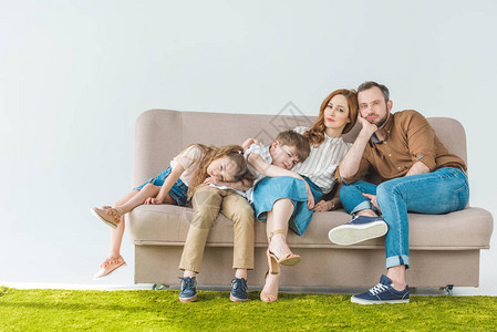 有两个孩子的家庭在沙发上休息用灰色的图片