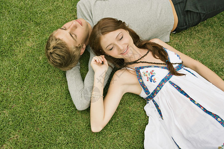 在公园里躺在绿草地上的一对年轻夫妇的头部肖像上图片