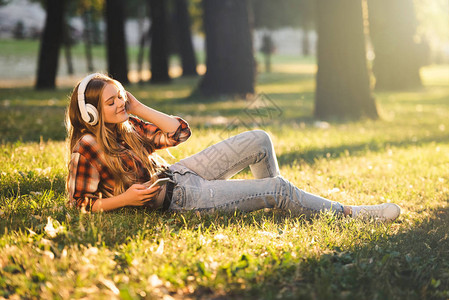 穿着休闲服的漂亮女孩躺在阳光下的草地上图片