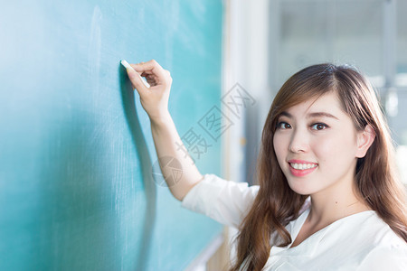 教室里有绿色黑板的漂亮年轻女孩图片