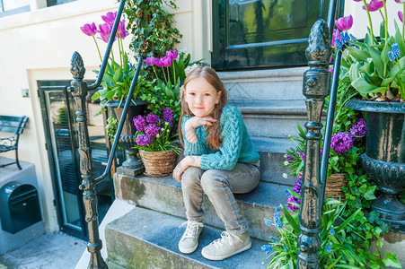 一个可爱小女孩的户外肖像坐在城市的台阶上背景图片