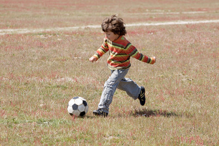 小孩子在球场上踢足球图片