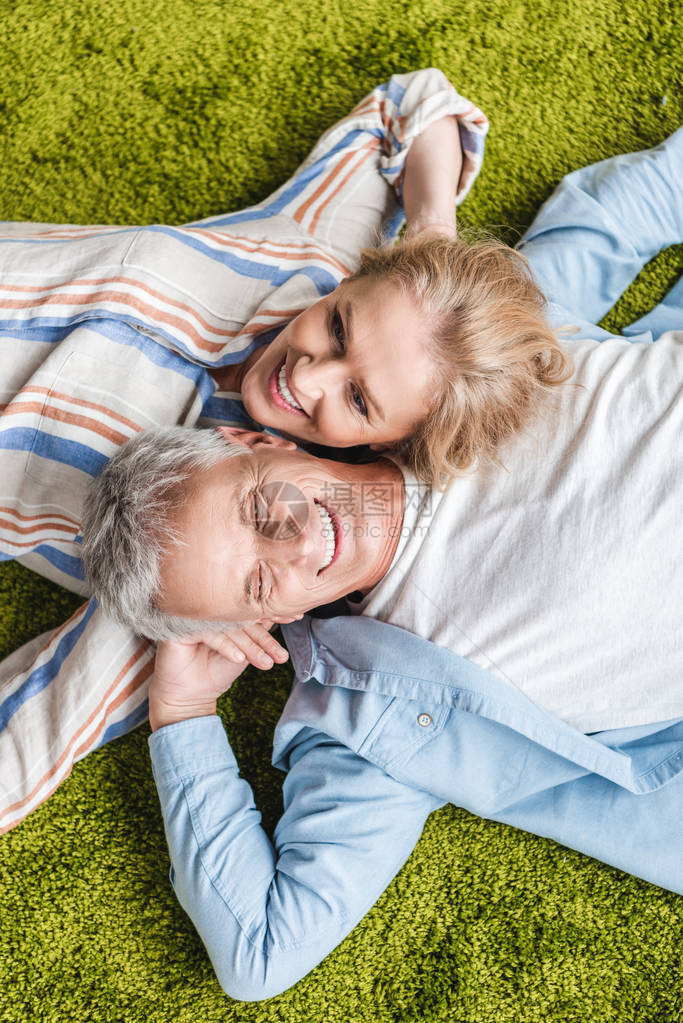 幸福的老夫妇在绿地毯上躺图片