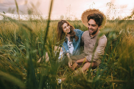 快乐的一对时尚夫妇草帽坐在草原图片