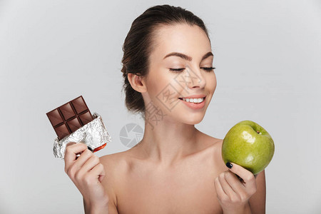 年轻女在苹果和巧克力之间做出抉择图片