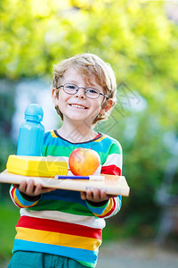 快乐的小男孩在上小学或幼儿园的第一天带着书苹果和饮料瓶户外回到学校图片