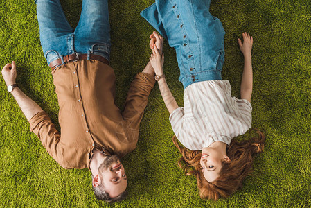 幸福的情侣躺在绿色的草坪上图片