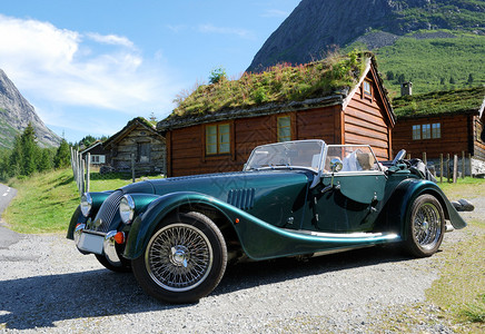 挪威山村是在夏天拍摄的绿屋顶的小木屋前停着一辆老式跑车背景图片