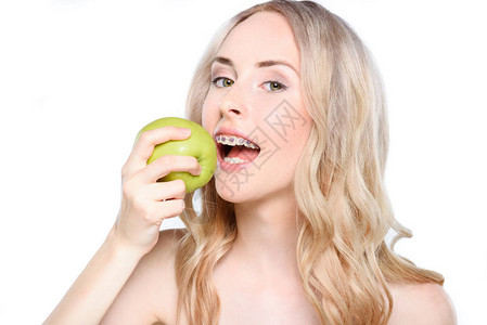 一个带着牙套的年轻女人吃了一口新鲜绿图片