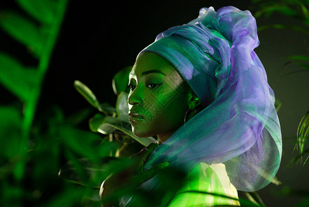 穿着铁丝头巾的有吸引力的非洲女在树叶后面图片