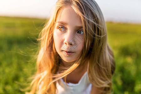 日落光线下绿色田野上可爱小孩的特写肖像图片