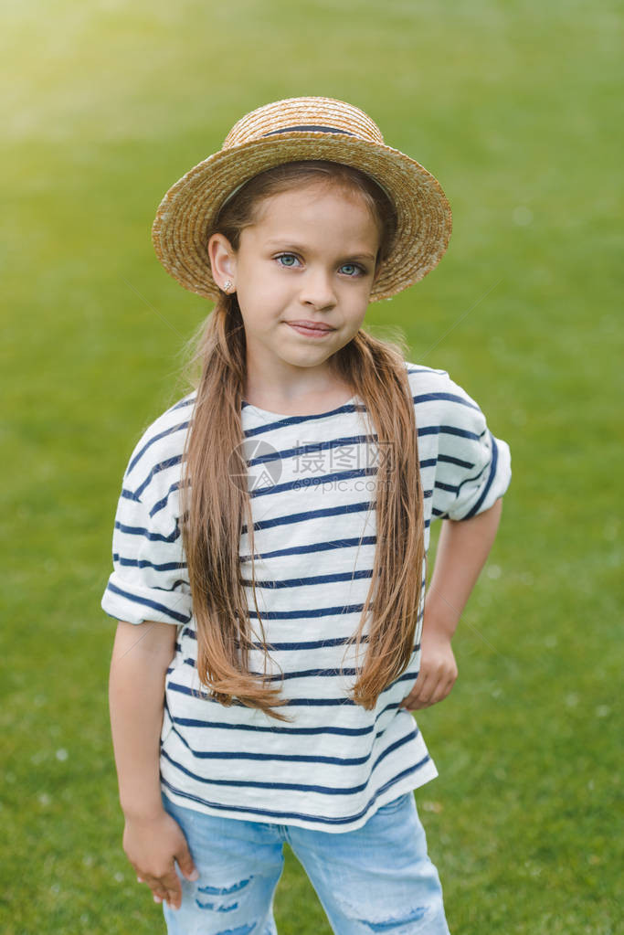 穿着草帽的可爱小女孩手靠腰站着看公图片