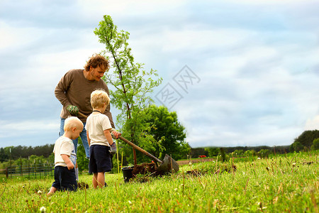 一个年幼的父亲和他的两个孩子在外面图片