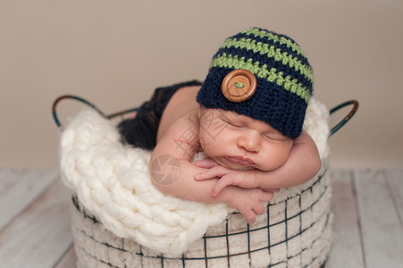索梅尔三个星期前刚出生的婴儿男孩穿着牛仔裤和一顶被编织的蓝色绿豆帽背景