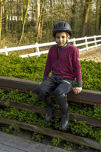 穿着头盔和靴子的可爱十几岁的男孩骑马图片