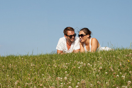 坐在山顶的草地上与明蓝晴阳天相对立的阳光下太阳镜里的浪漫图片