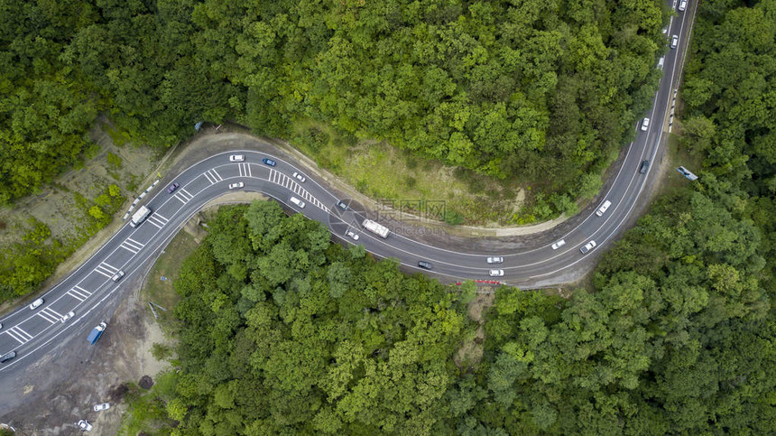 汽车沿着蜿蜒的山口公路穿过俄罗斯索契森林的空中库存照片图片