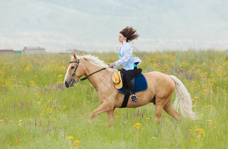 那个女孩骑着马在一片绿色的田野上跳跃图片