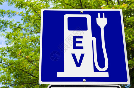 具有绿树背景的电动车辆充电车站标志图片