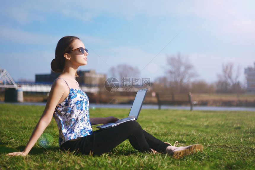 女人坐在公园里的绿色草地上图片