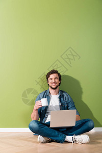 男人拿着咖啡杯和笔记本电脑图片