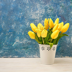 蓝色背景的花瓶中的黄色郁金香Bouquet图片