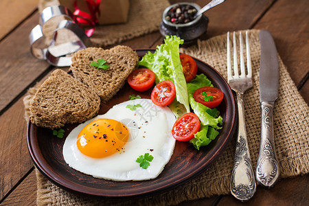 情人节早餐煎鸡蛋和面包以心脏和新鲜蔬图片