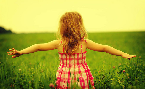 女孩在草地里享受大自然日出时伸展图片