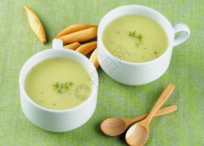 两杯白汤杯中配着面包棒和木薯条的美味果汁牛排汤紧贴绿色图片