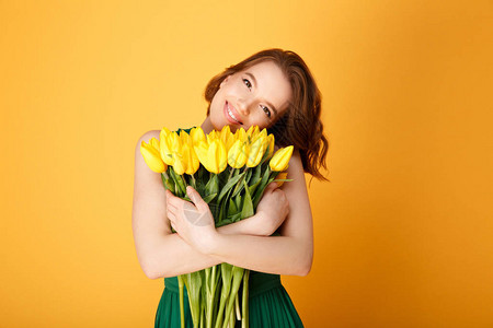 面带微笑的女人拥抱着黄色郁金香花的肖像在图片