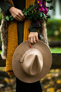 秋时装细节帽子羊毛围巾皮衣和手握花束图片