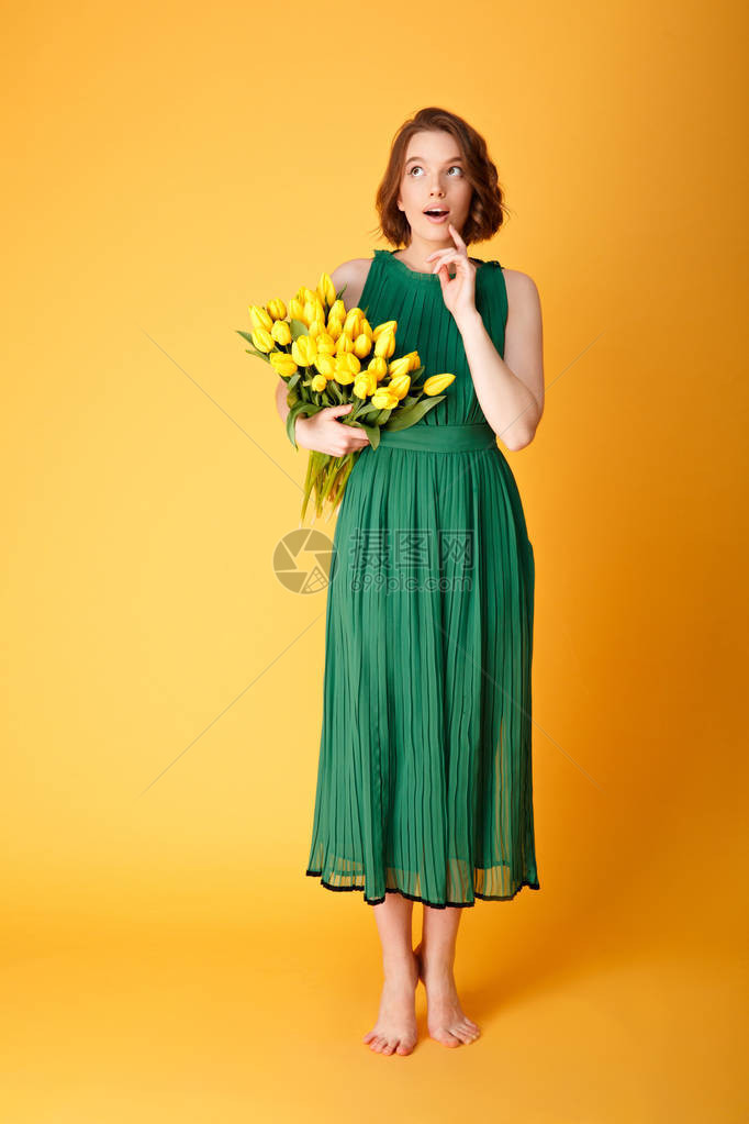 身着绿裙子的年轻阴柔女人带着一束黄色郁金香花望图片