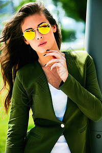 身戴黄色太阳镜和绿色夹克的年轻城市时装女图片