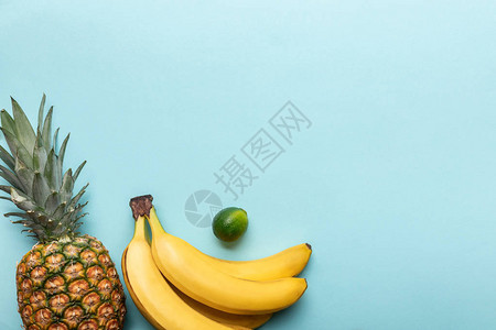 满熟菠萝香蕉和石灰的顶部视图蓝色背景图片