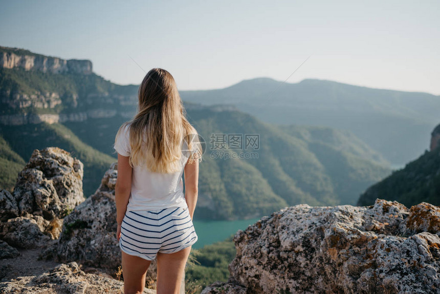 一位身穿白色T恤和白色短裤的可爱年轻女子站在山顶上图片