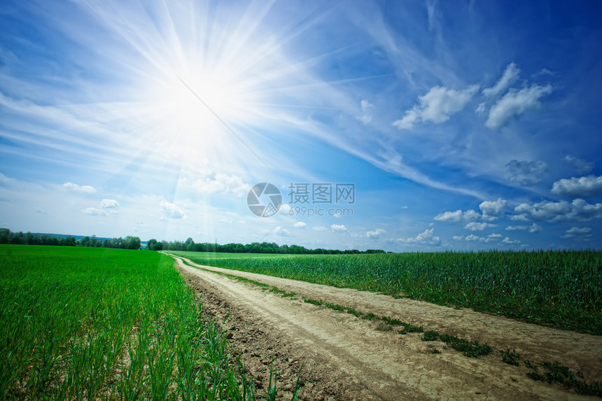 风景与乡村道路穿过田野和多云的天空图片