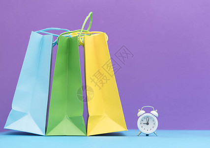 紫色背景中的彩色购物袋和闹钟图片