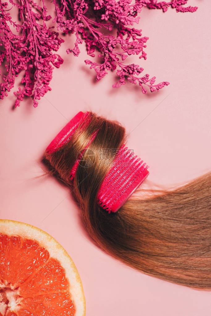 头发卷在发器上的顶部视图粉红色表面图片