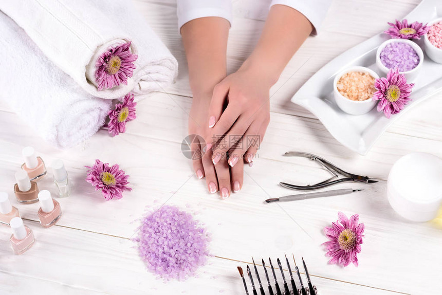 用毛巾鲜花指甲油彩色海盐奶油容器和美容院修指甲工具在餐桌图片