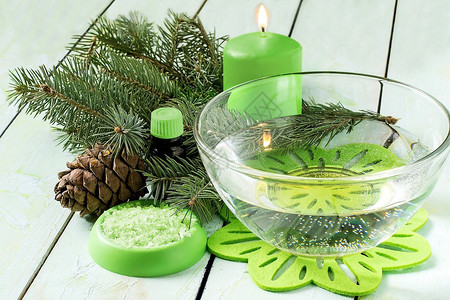 用锥体海盐瓶中油和浅绿色漆木背景上的香味蜡烛沐浴图片