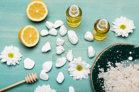 木桌上的海盐瓶装油柠檬片和洋甘菊的顶视图图片