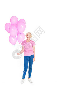 身穿粉色T恤戴着乳腺癌意识丝带的高级女拿着粉色气球图片