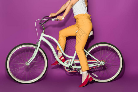 在紫罗兰色上隔离的时尚女孩骑自行车的短片图片