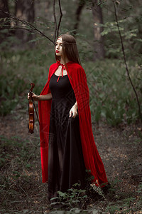 穿着红色斗篷的迷人神秘女人在黑暗的森林图片
