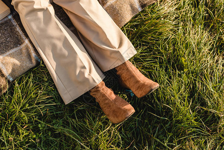 户外草地上穿着麂皮棕色鞋的女腿的低段图片
